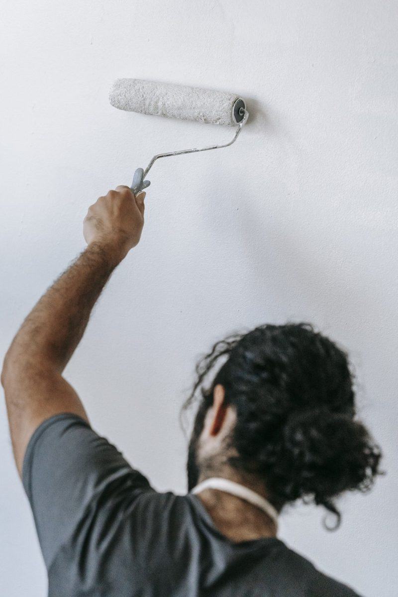 Painter rolling white paint onto an interior wall