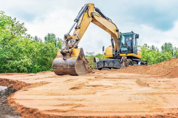Excavator grading and levelling bare earth on a building plot